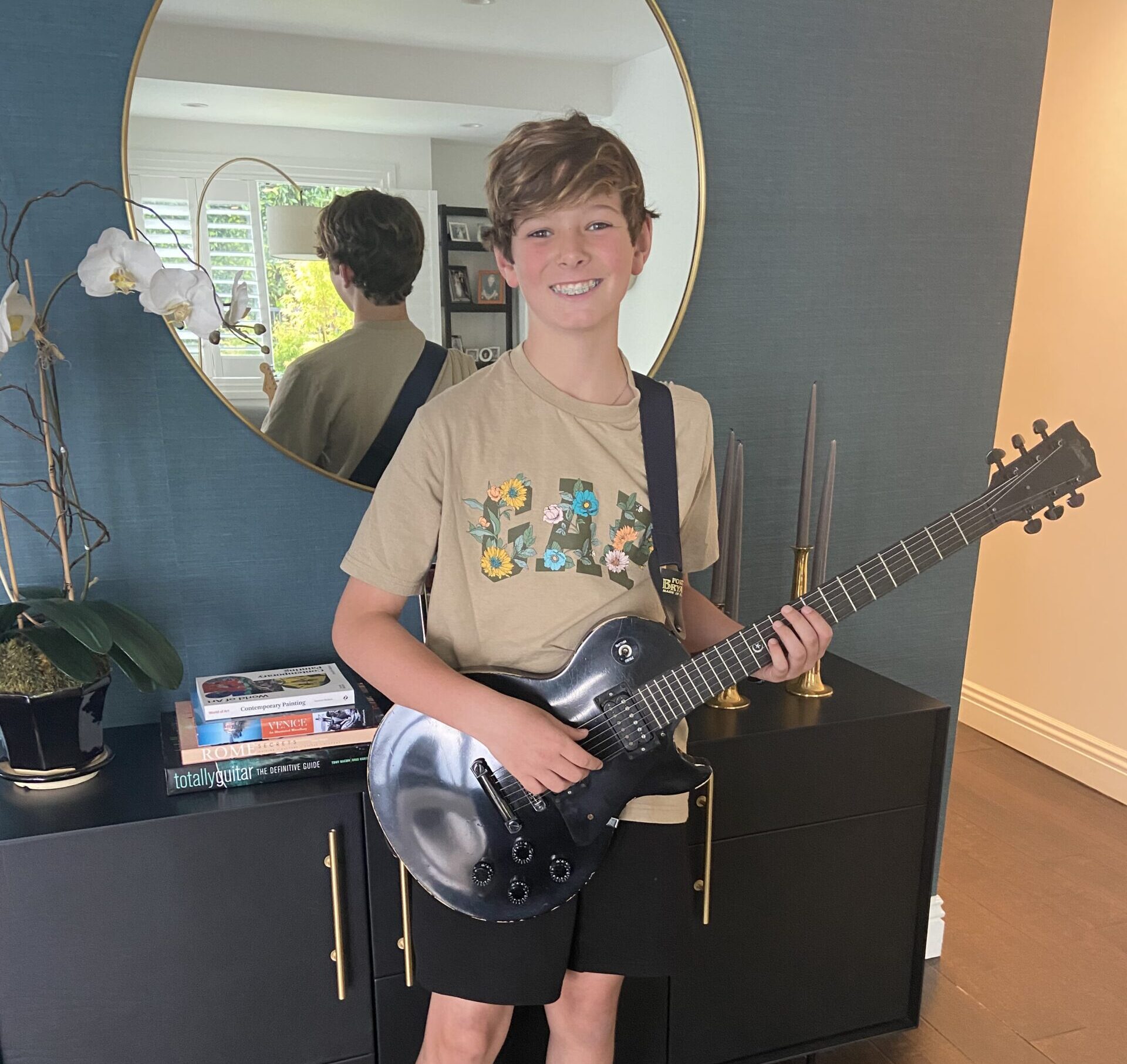 young boy at his home holding his electric guitar