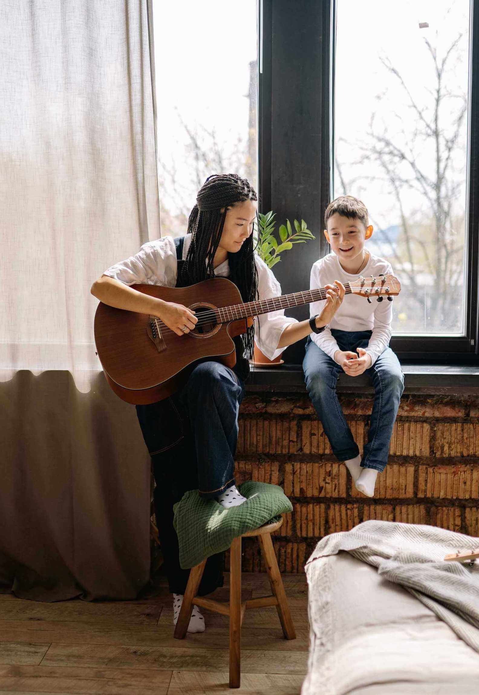 guitar teacher teaching the kid play the guitar at home