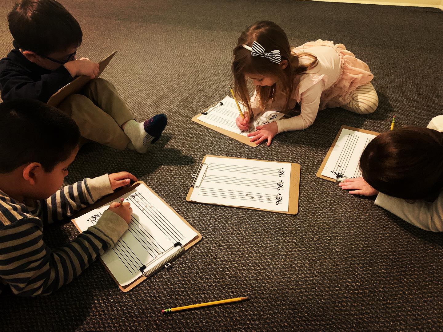 Group of kids on the floor writing in music workbooks