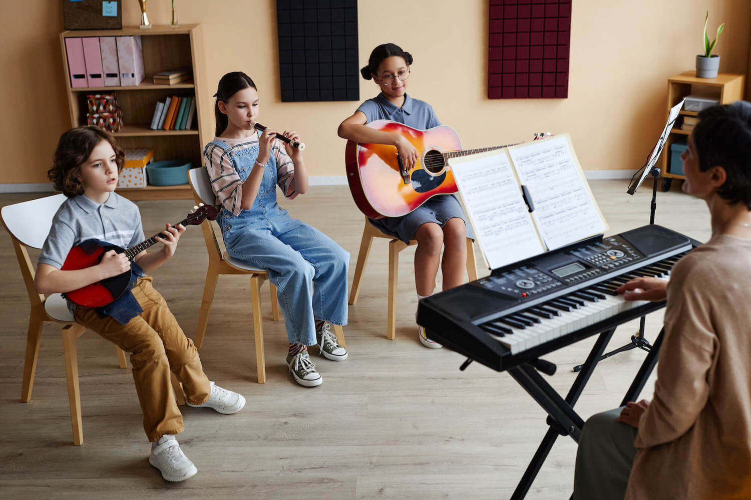 three students two of them playing the guitar and one of them playing the flute