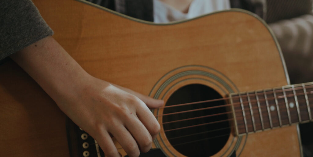 student playing the guitar with a close up of the guitar