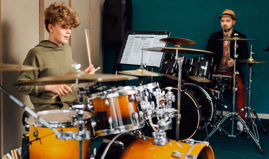 student learning to play the drums at home with a drum teacher