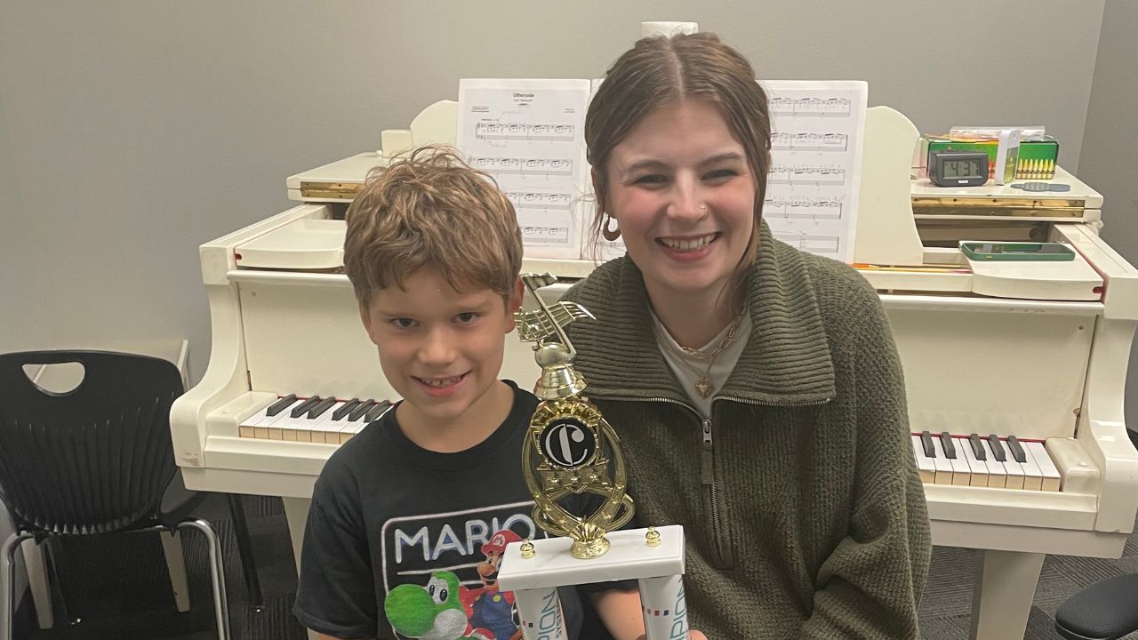 Student holding award with teacher -cappella music academy