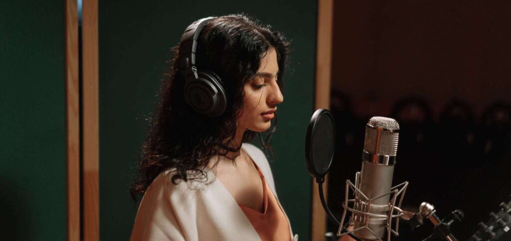 student singing into a microphone with headphones on