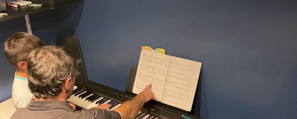 student and teacher playing piano