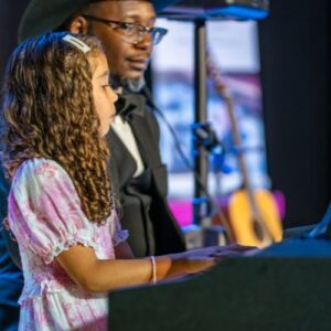 a piano student and her teacher performing during a recital