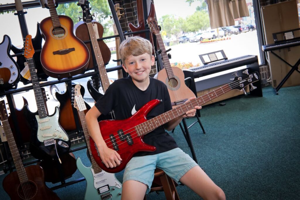 student holding a bass guitar in the music shop
