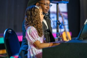 a piano student and her teacher performing during a recital