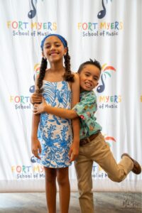 Dos hermanos abrazándose mientras están parados frente a nuestra pancarta de paso y repetición.