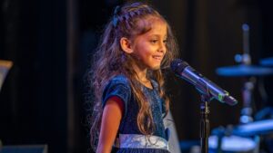 student standing on stage in front of a microphone during a recital