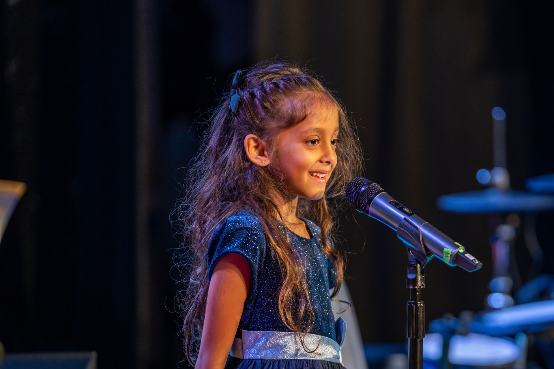 student standing on stage in front of a microphone during a recital