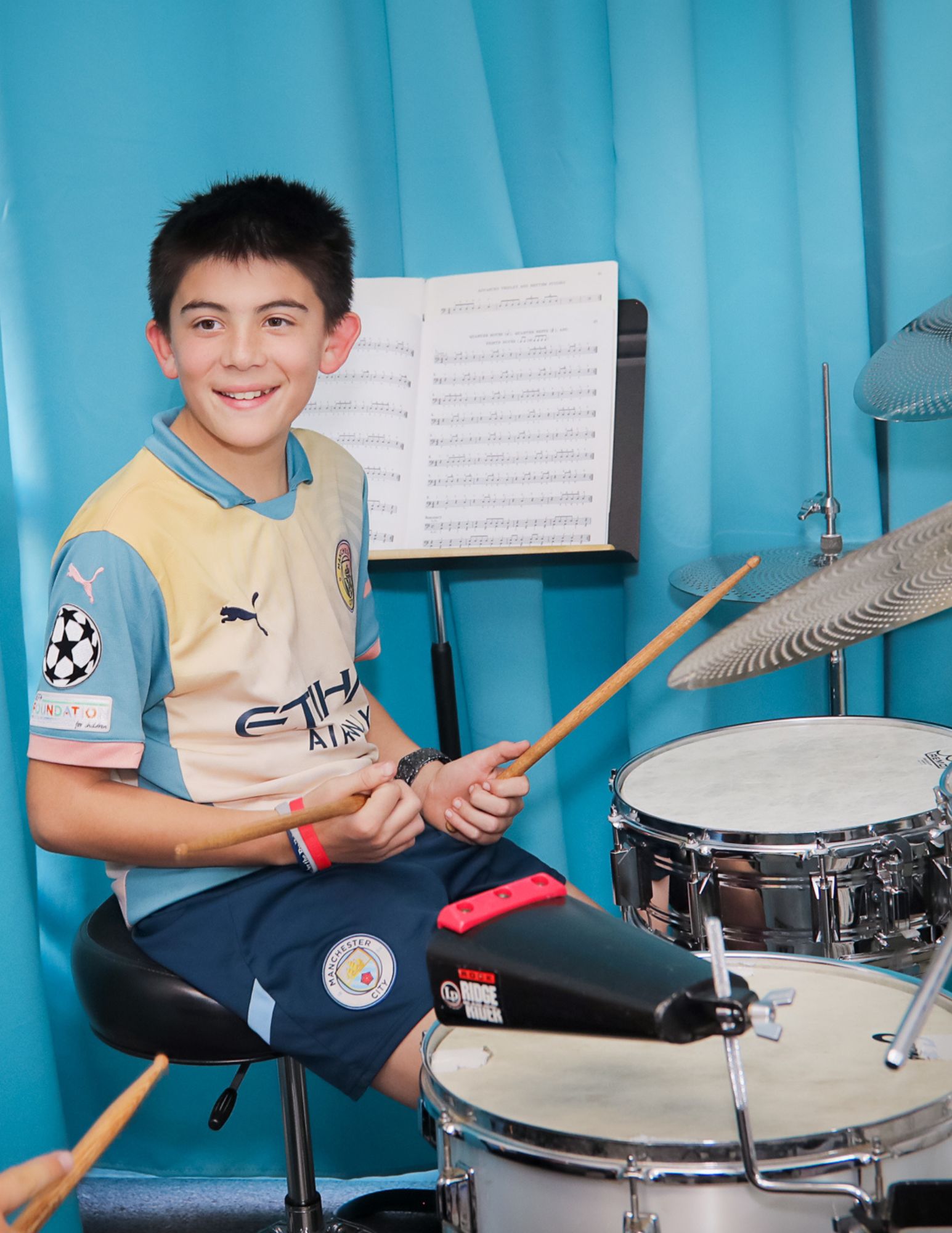 Young boy sitting at a drum set and smiling