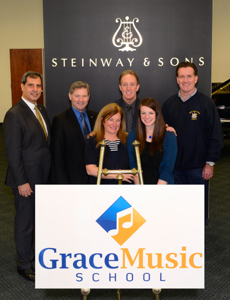 the Heaphy family standing with the grace music school logo in front of the steinway and sons logo