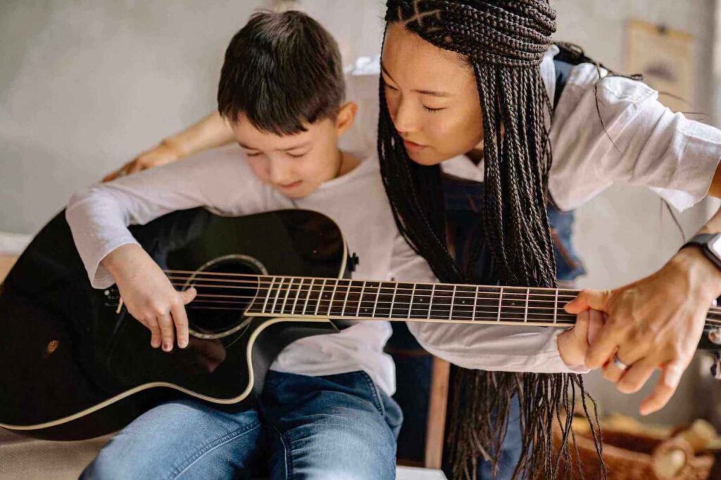 guitar teacher teaching the kid play the guitar at home