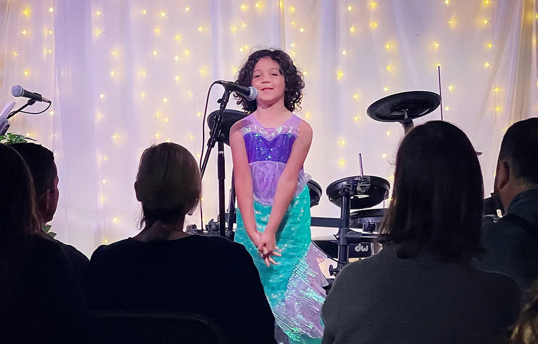 Girl in singing on stage at Green Brooms Music Academy recital