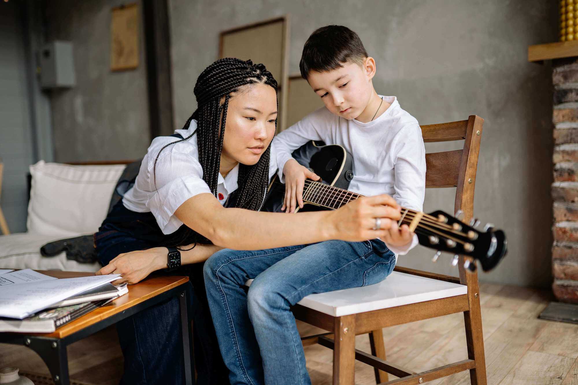 guitar teacher teaching the young student to play the guitar in Geneva, IL