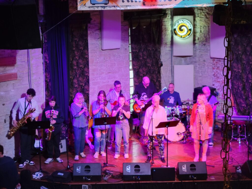 a band with brass, woodwind, and vocal students performing