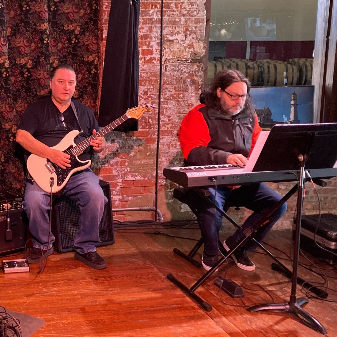 two instructors performing on stage, one on the left with an electric guitar and one on the right with an electric keyboard