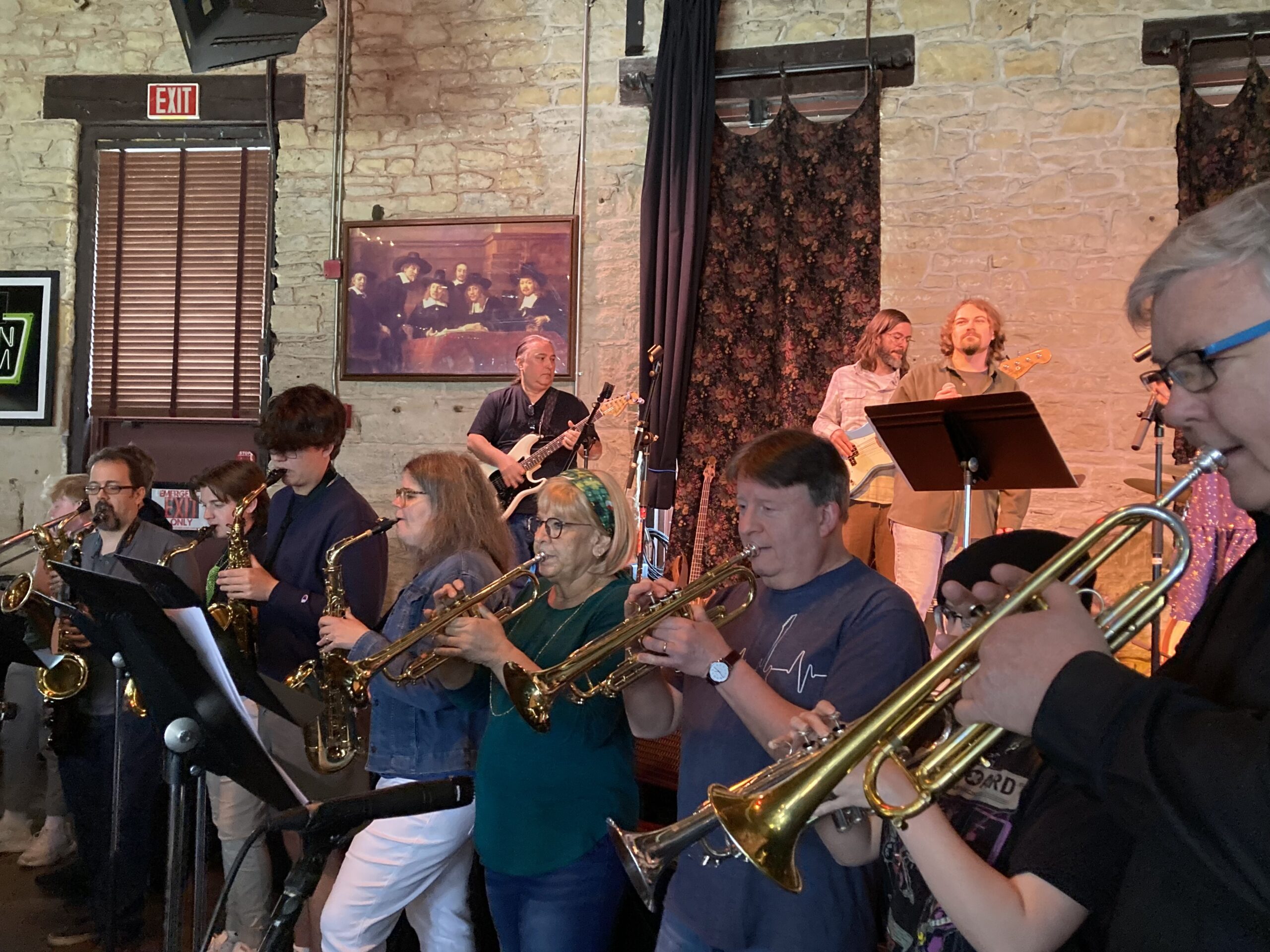 students and teachers performing together playing both brass and woodwind instruments