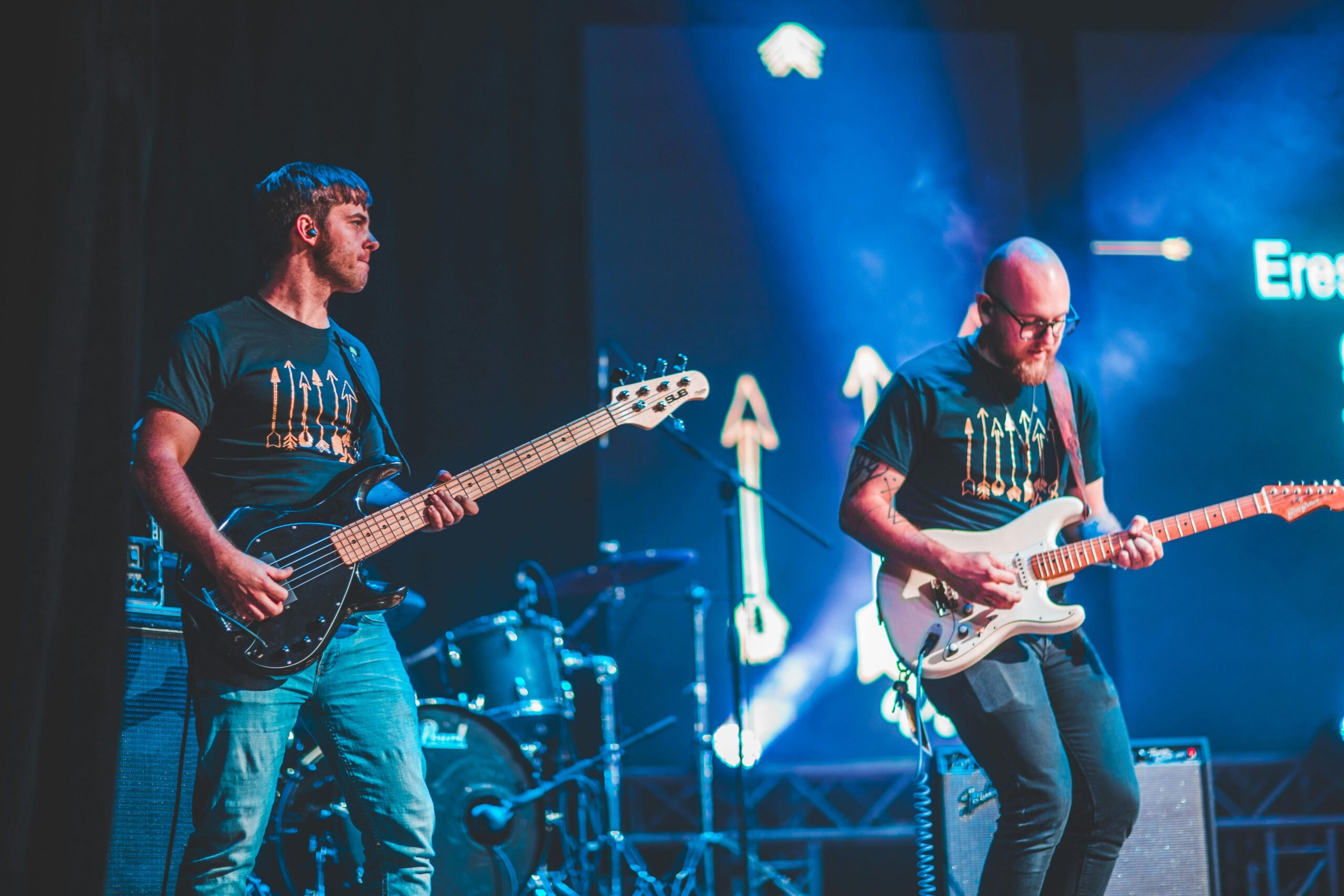 Energetic live performance featuring guitarists on stage with vibrant lighting.