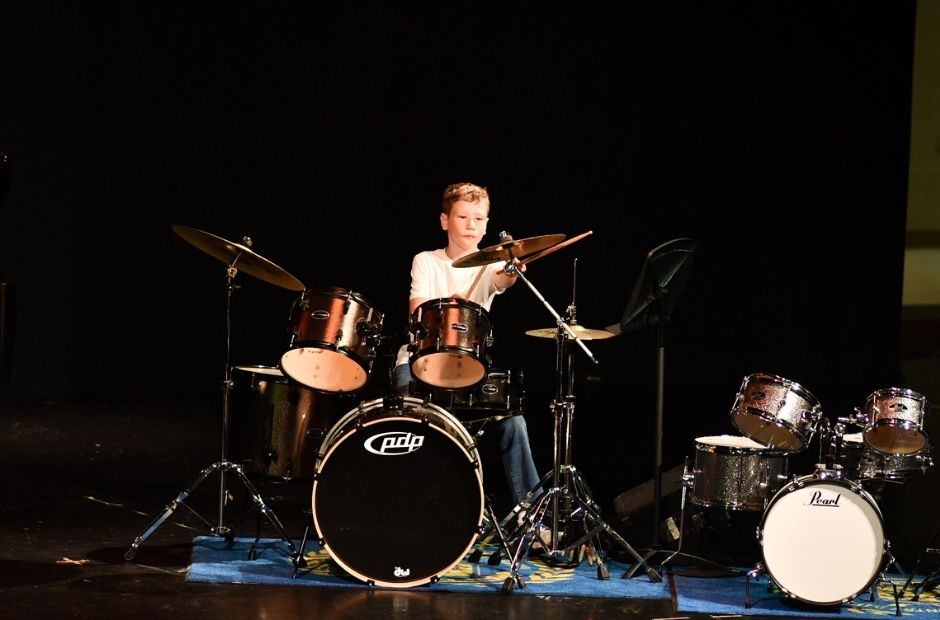 student playing drum set at a recital