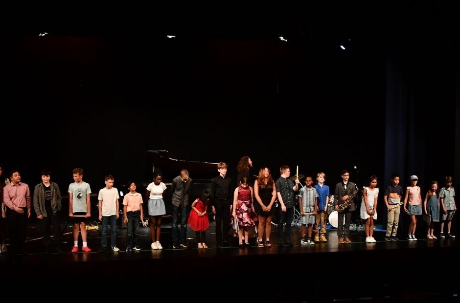 group of students standing on stage after a recital