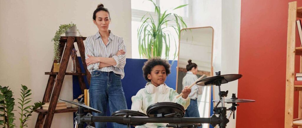 student learning to play the drums with a teacher at home