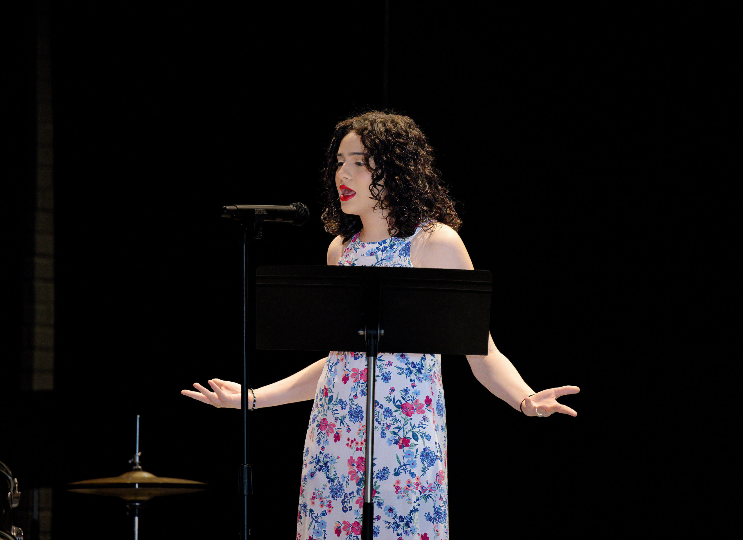 Girl with curly hair singing on stage