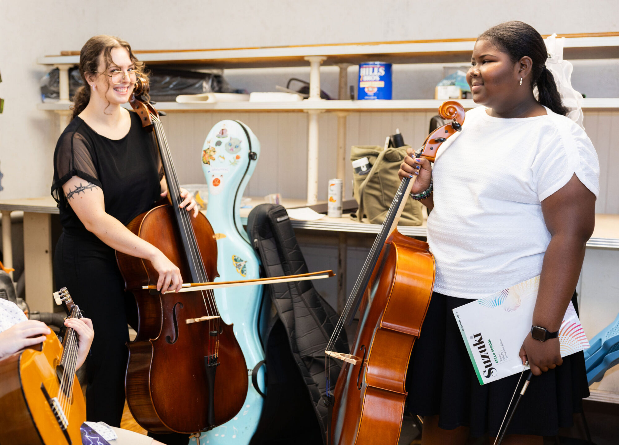 Two cello students holding their cellos and smiling