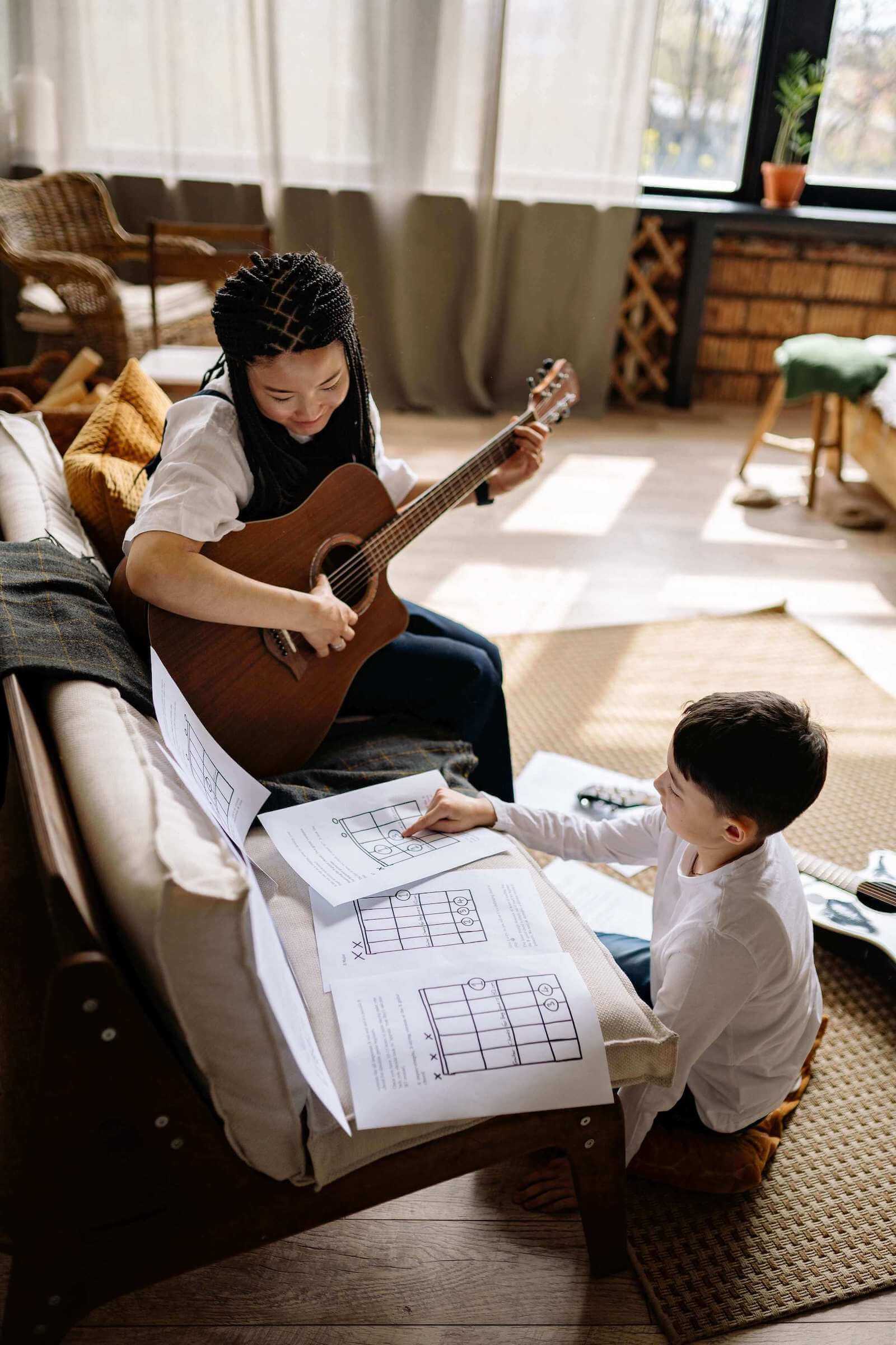 guitar teacher teaching the kid play the guitar at home