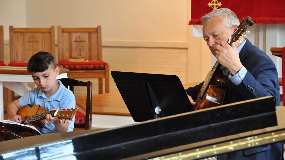 guitar teacher and student performing together during a recital 