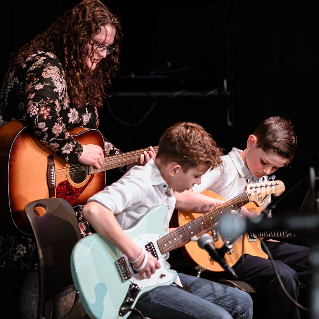 Students playing guitar with teacher, loveland CO