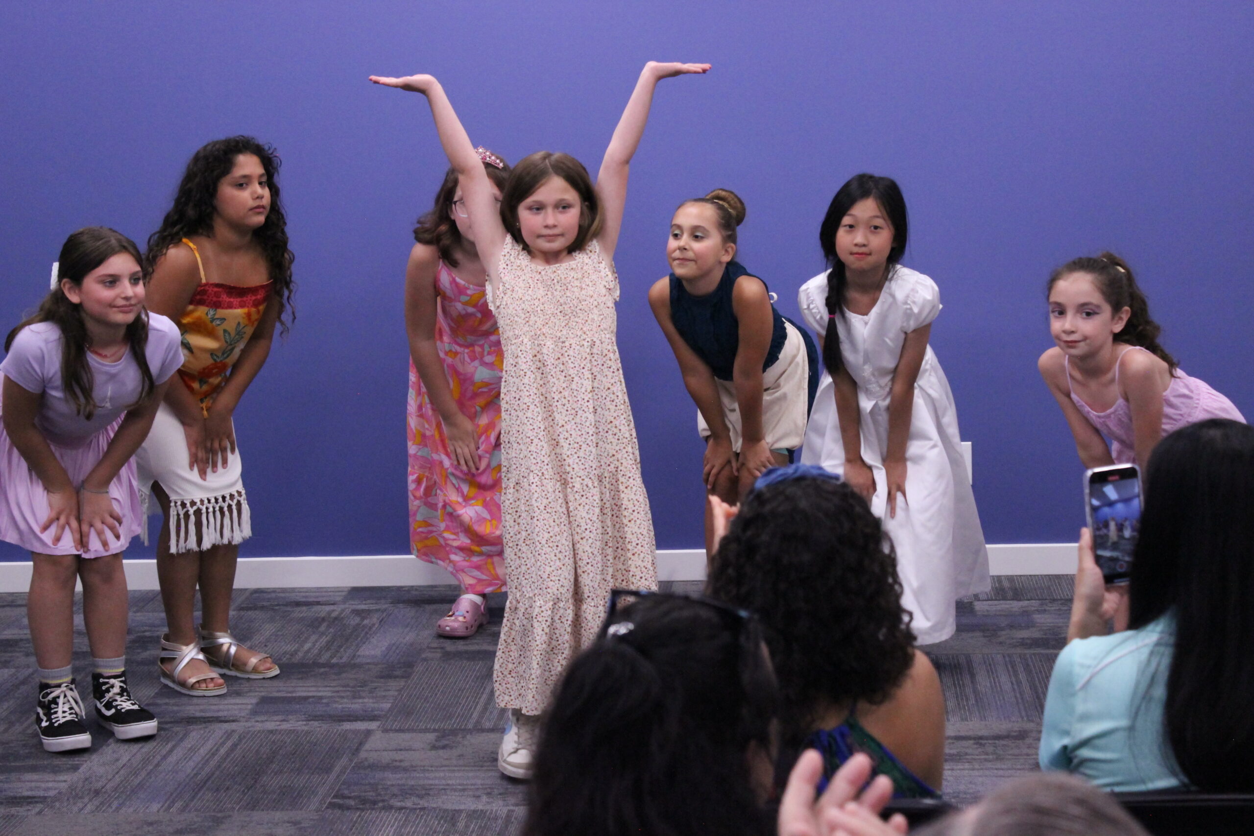 Group of kids performing, with one child in the middle with her arms up