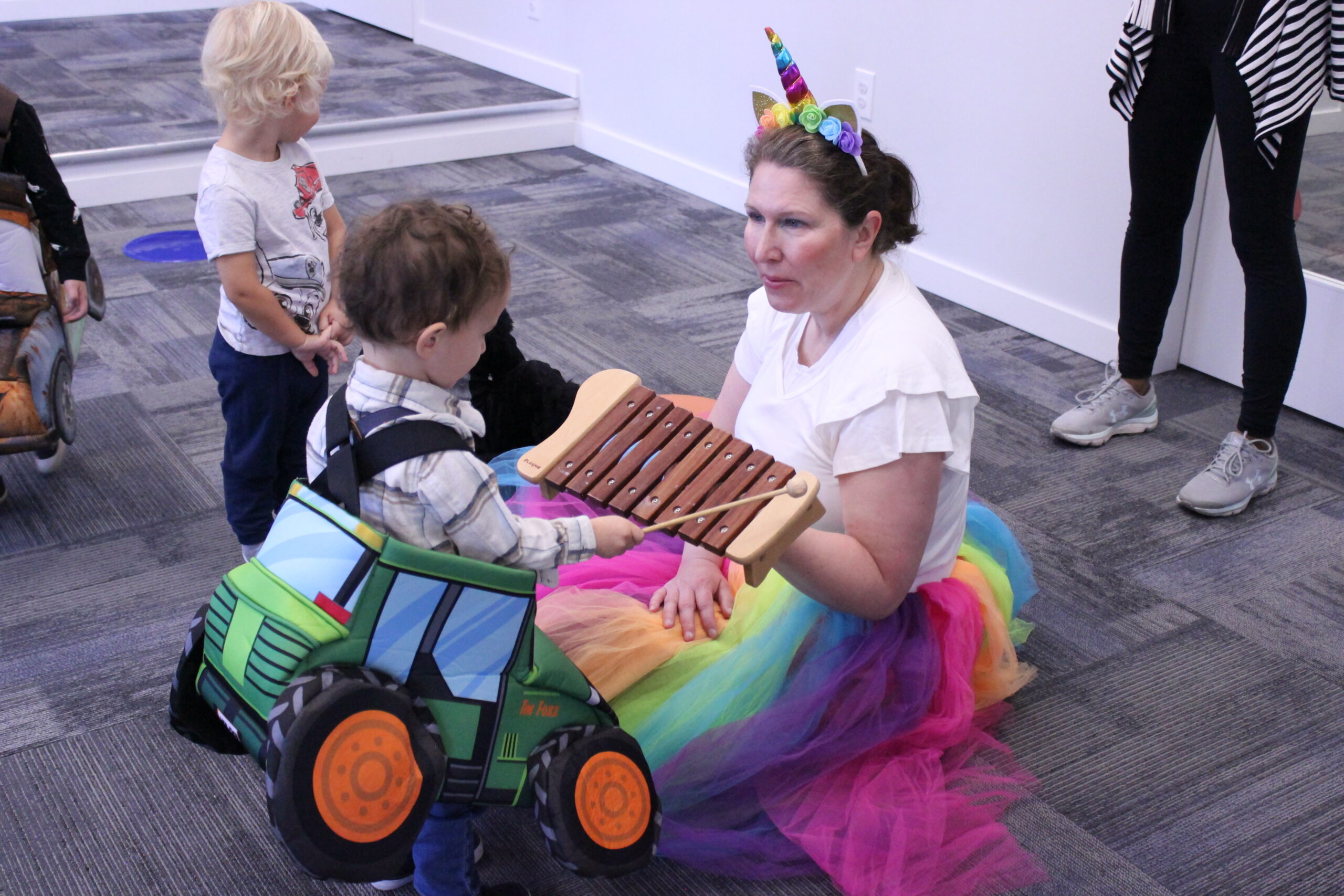 Teacher dressed as a unicorn holding up a xylophone for a child in a car costume