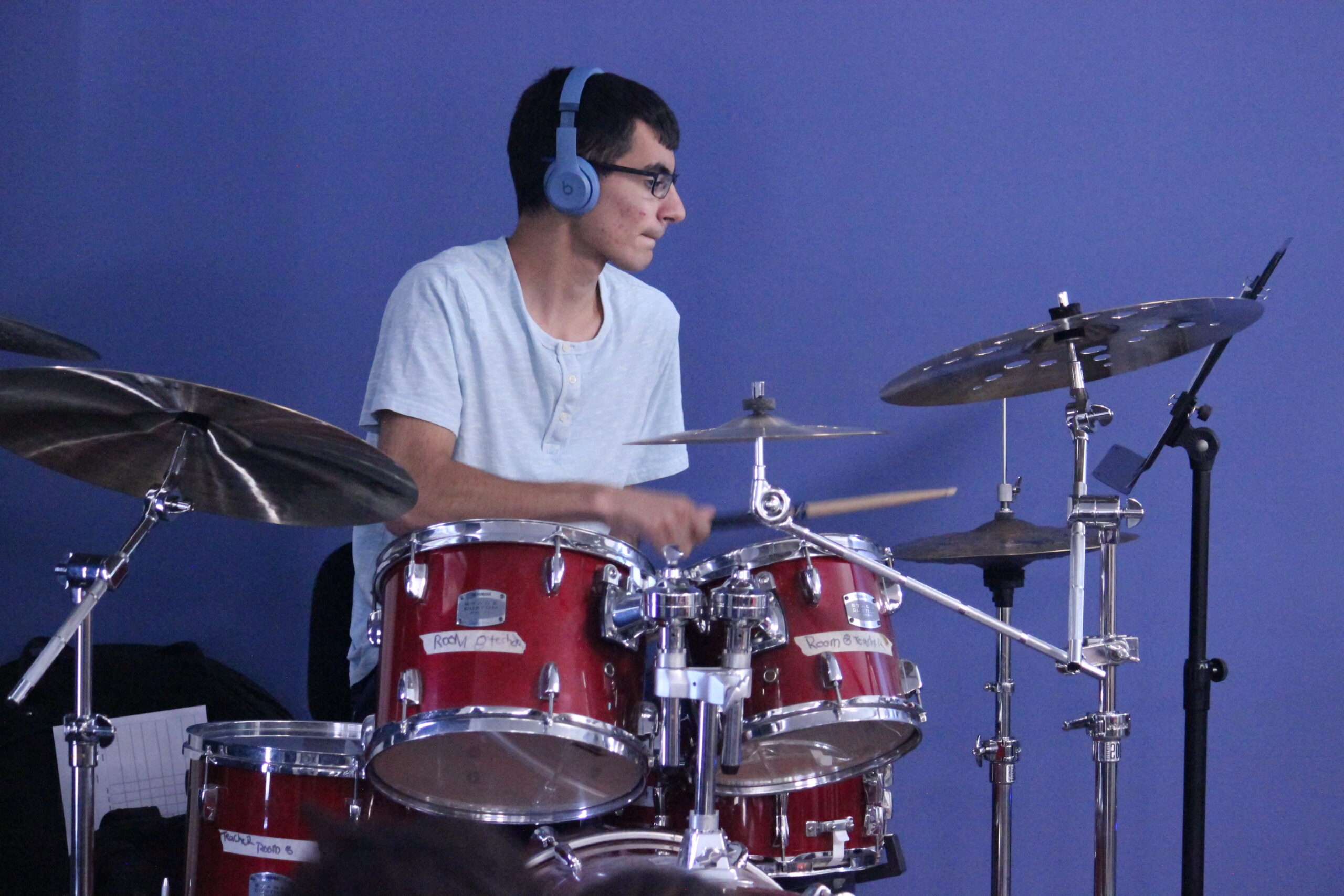 Student with blue headphones playing drums