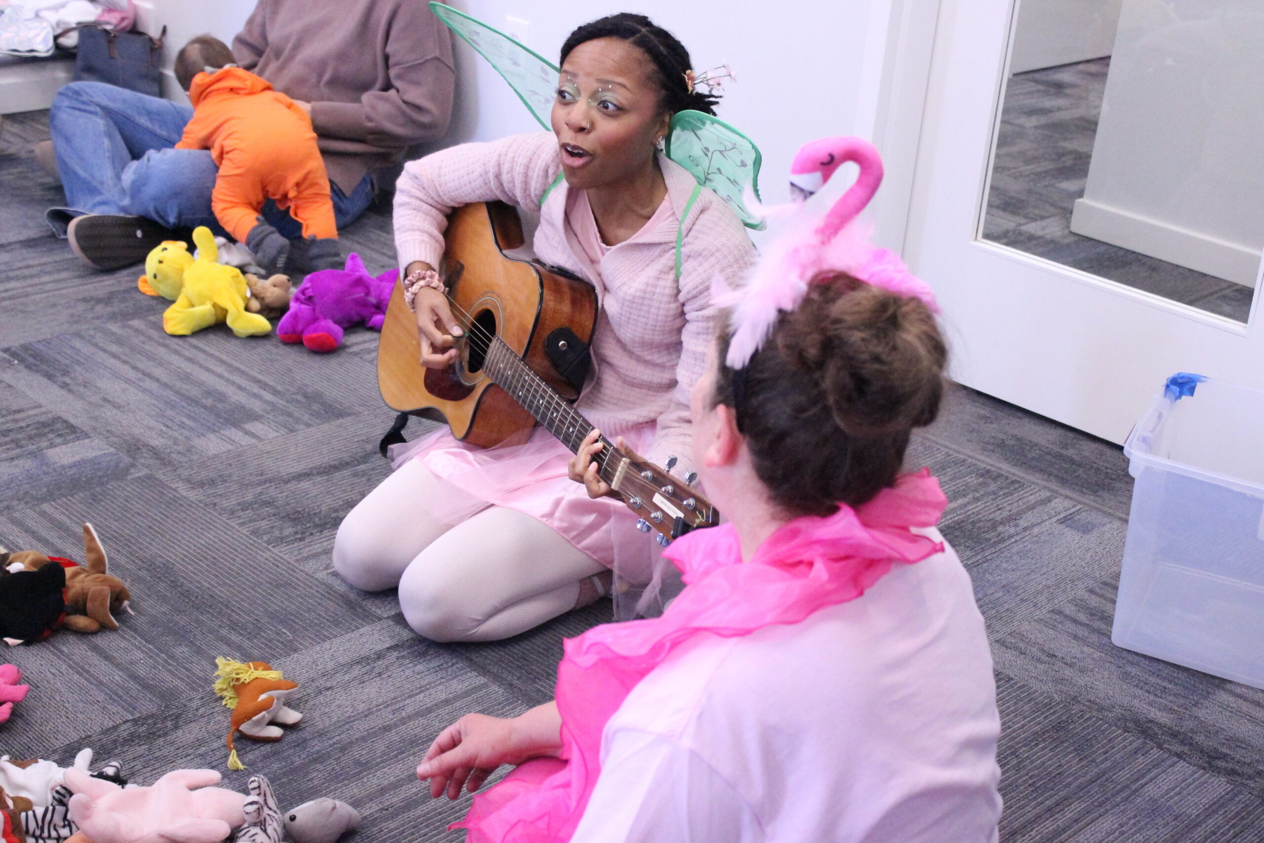 Teacher in a pink fairy costume playing an acoustic guitar