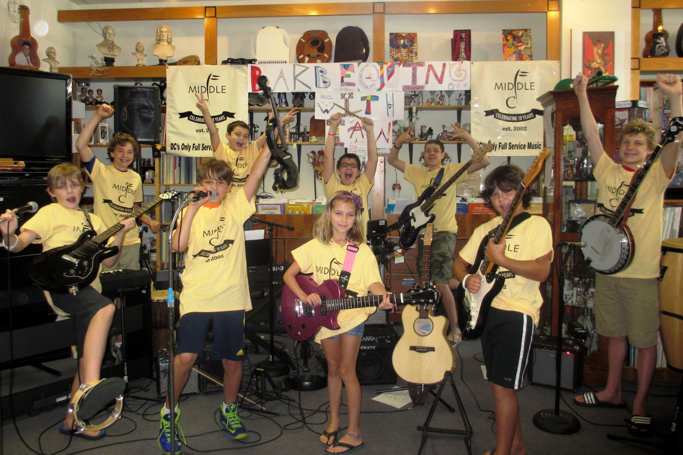 group of students holding their instruments in the store while wearing yellow middle c shirts
