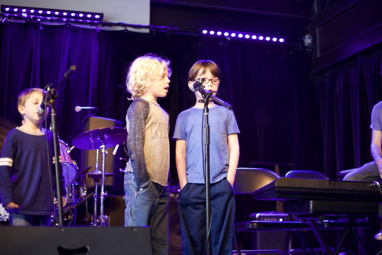 two young boys singing into a microphone on stage