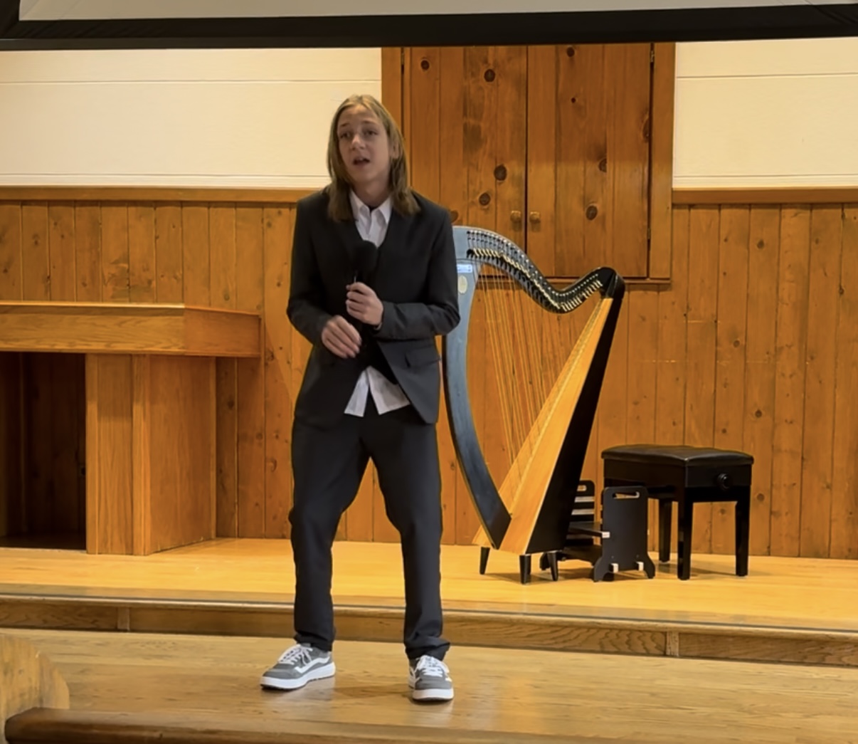 Boy in a suit singing on stage