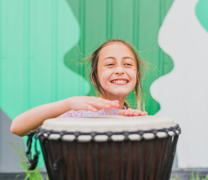 young girl smiling and playing the djembe