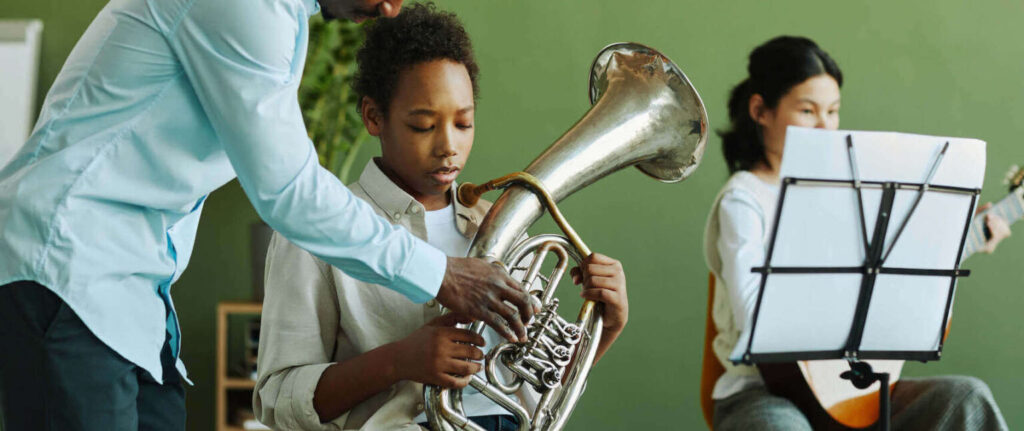 teacher teaching the student how to hold a french horn