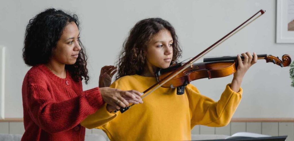 teacher helping the student hold the violin