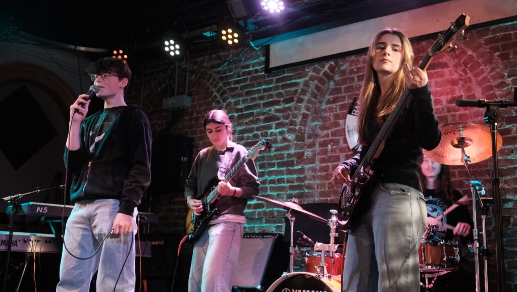 students performing in a rockband on stage