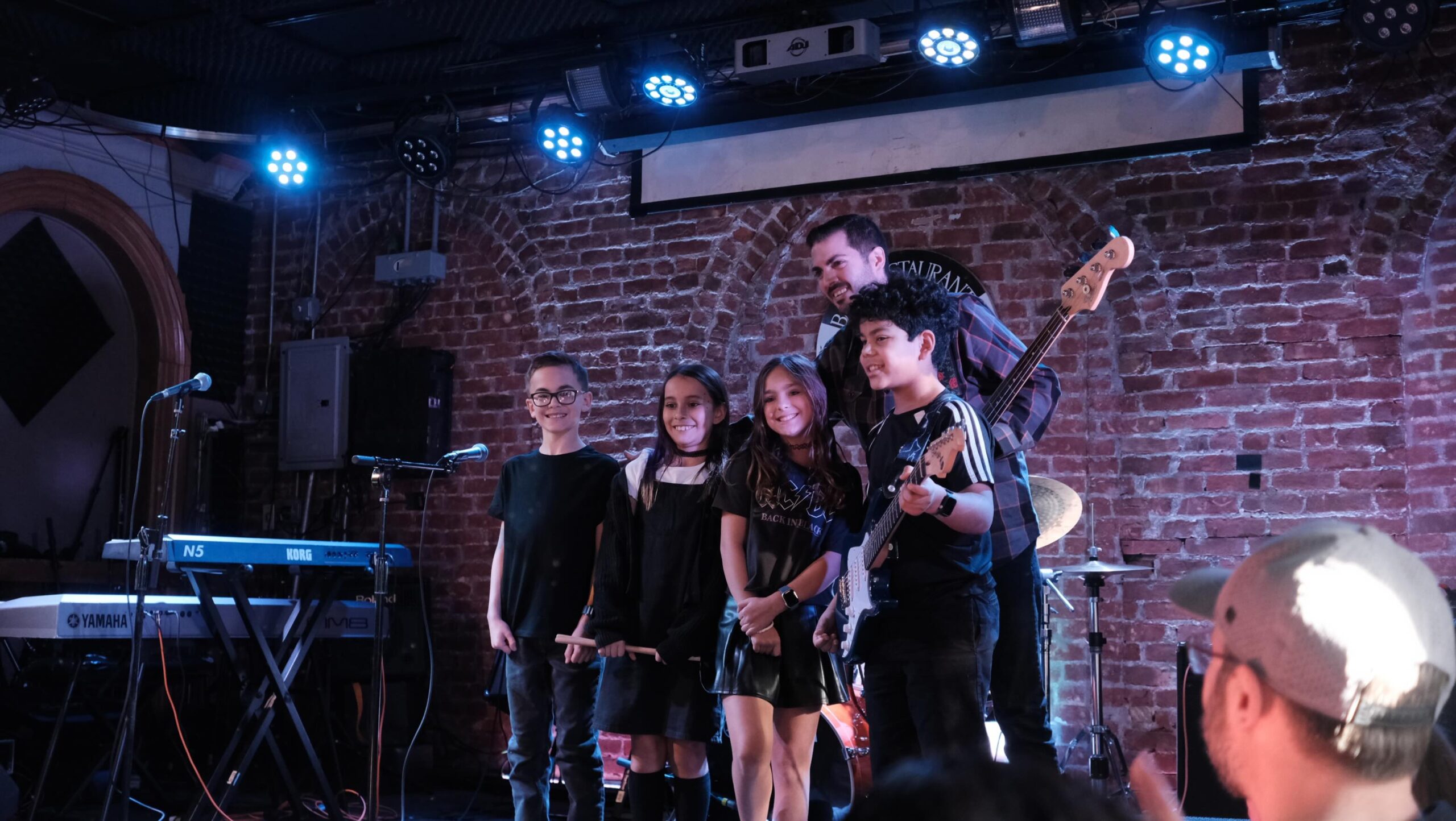 children standing on stage with their teacher smiling