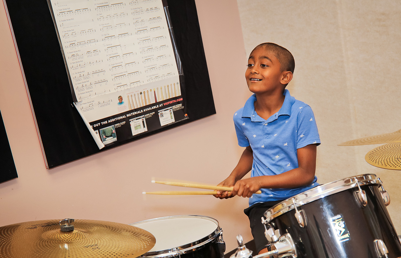 Young boy playing the drums and smiling