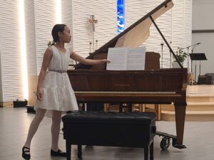 Girl grabbing sheet music off of piano on stage
