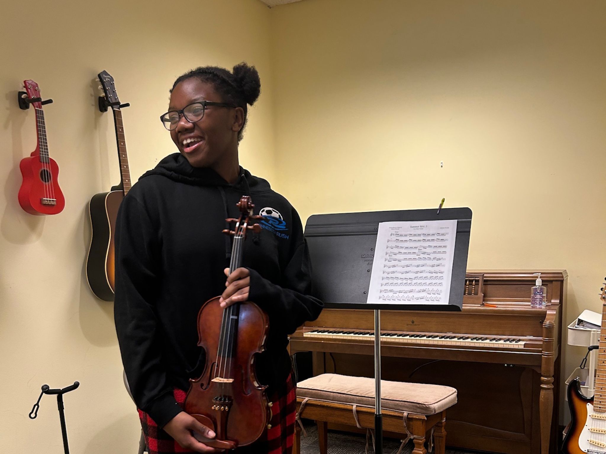 Girl smiling and holding up violin