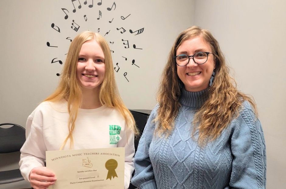 teacher and student smiling together while the student holds up an award