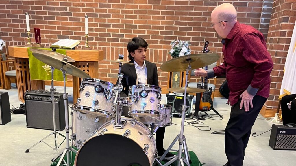Student learning to play drums with teacher