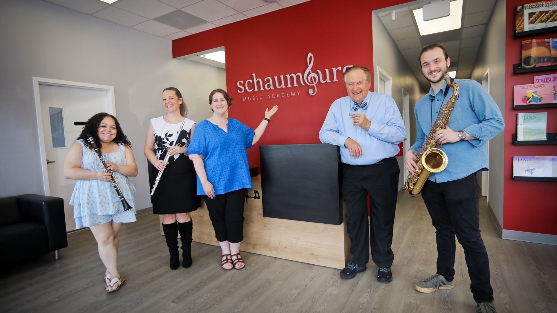 staff standing at the front desk in front of the school logo on the wall